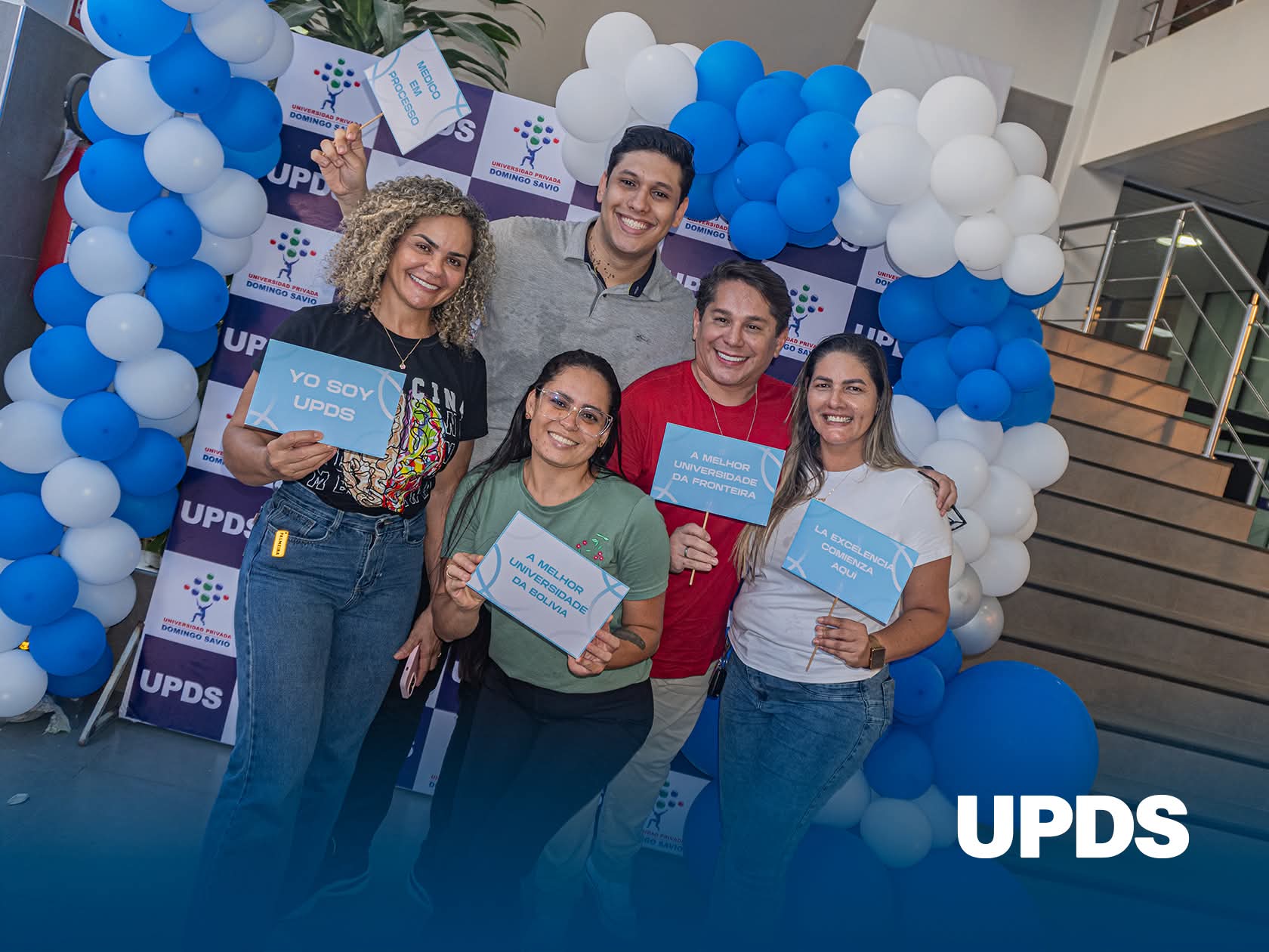 Estudiantes internacionales dando la bienvenida en UPDS Cobija con carteles en español y portugués
